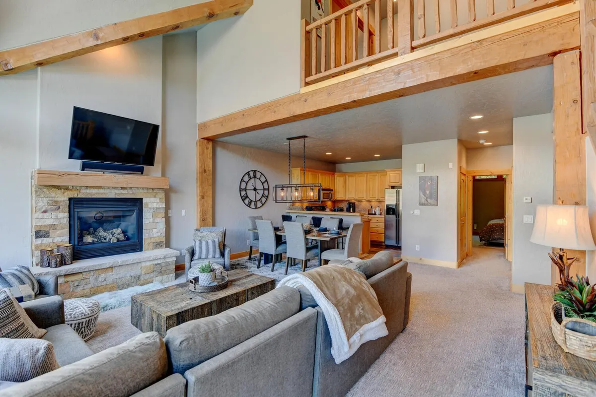 A cozy, open-concept living space where the dining area and kitchen flow into a lounge with a fireplace and comfortable seating. The scene captures a family enjoying meals, socializing, and relaxing together, highlighting the home’s interconnected and inviting design.
