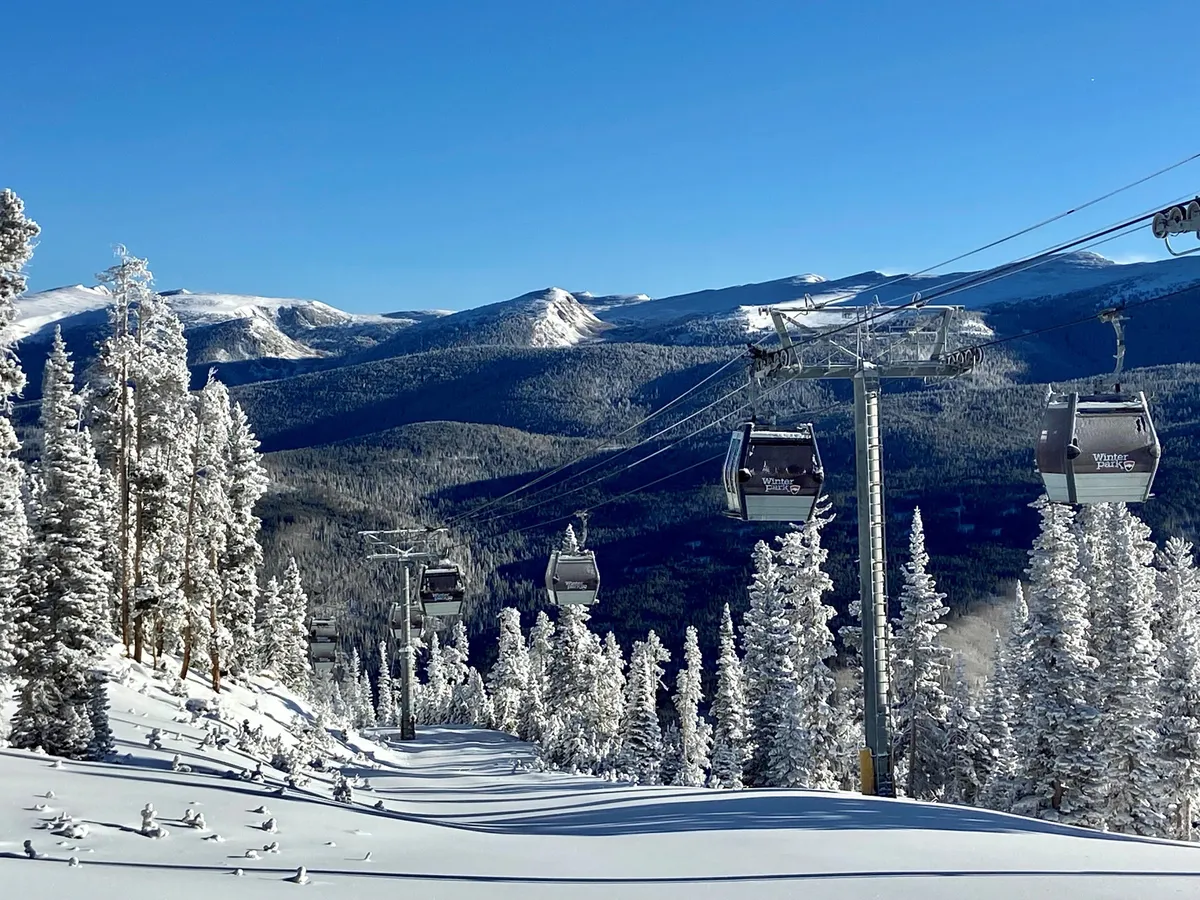 This image captures a snowy mountain landscape with ski lift gondolas gliding above snow-covered trees and distant mountain peaks. The scene is alive with activity, showing people engaging in skiing, snowboarding, and snowshoeing, all set against a backdrop of breathtaking panoramic views.